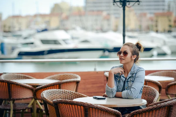 Beautiful young casual style woman sitting alone at cafe outdoors — Stock Photo, Image