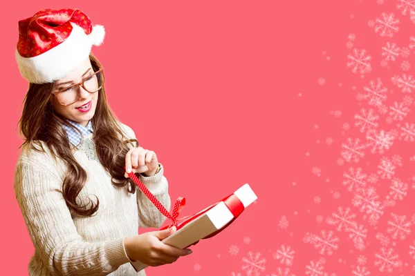 Счастливая романтичная симпатичная девушка в красной шляпе и очках открывает подарочную коробку на праздничном фоне — стоковое фото