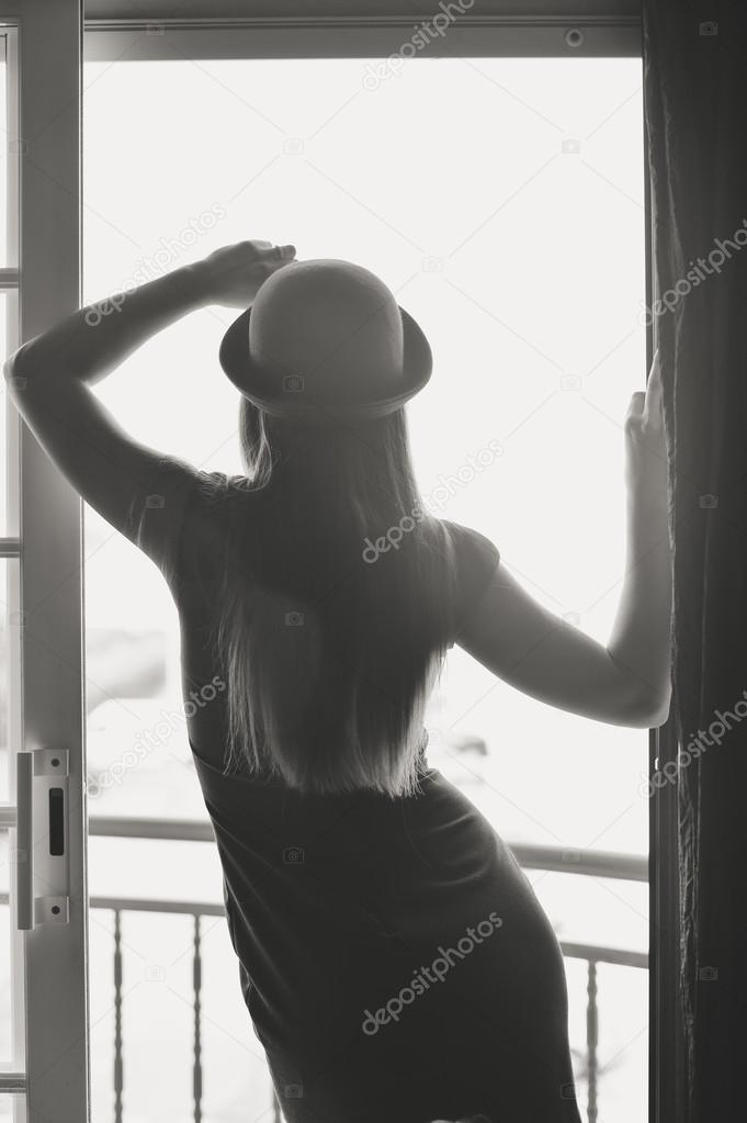 Monochrome back view of intriguing feminine lady standing in doorways