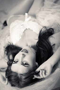 Sexy beautiful lady in white lingerie relaxing in bed, black and white portrait