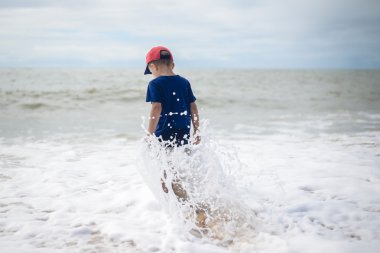 Small brave boy going to swim in rolling sea alone