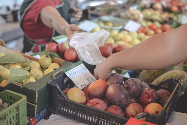 Persona que recoge frutas frescas jugosas del puesto en el mercado de frutas — Foto de Stock