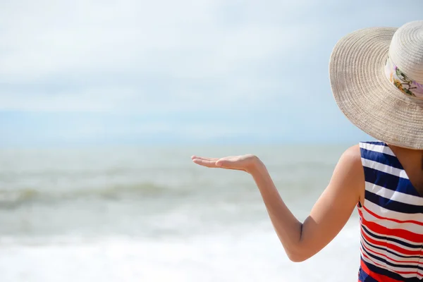 Lady in broadbrim hat facing sun standing on sandy seaside — ストック写真