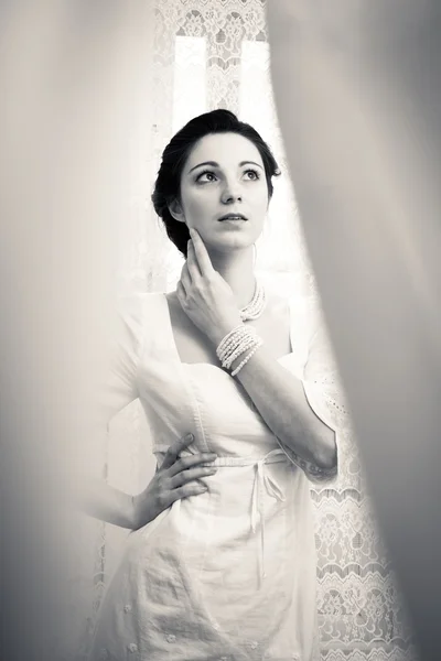 รูปภาพของสาวสวยสง่างามในชุดสีขาว มองขึ้นบนพื้นหลังม่านสําเนาพื้นที่ tulle — ภาพถ่ายสต็อก