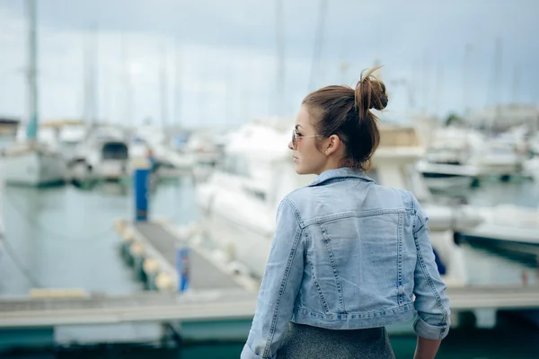 Side view of pretty girl standing on embankment with boats — Stockfoto
