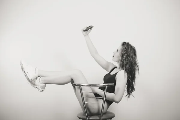 Beautiful young woman in black jumpsuit sitting and making selfie — Stock Fotó