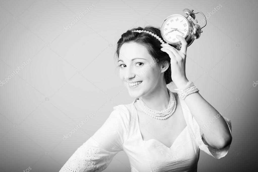 Picture of elegant beautiful young lady having fun holding alarm clock up and happy smile on copy space background. Black and white photography