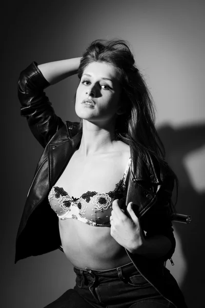 Picture of sexy beautiful young woman in leather jacket and lingerie posing and looking at camera over light copy space background. Black and white photography — ストック写真