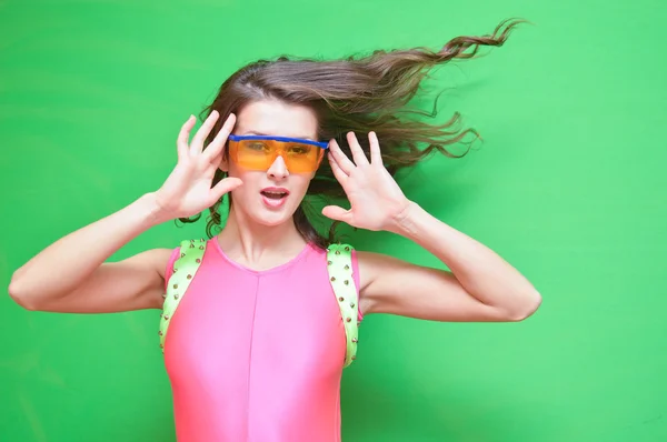 Signora con i capelli flipping indossando occhiali di sicurezza e tuta rosa — Foto Stock