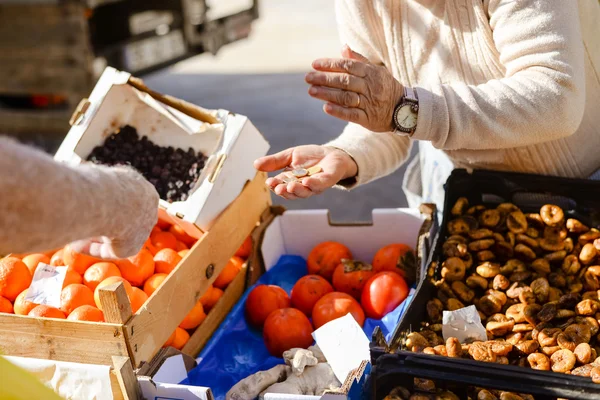 Consumer holding coins making purchases on fruit market stand background — Stok fotoğraf