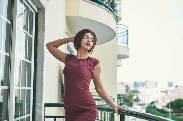 Superbe dame en robe rouge foncé posant debout sur le balcon — Photo