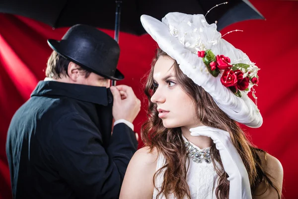 Lady in hat and mysterious man in black hiding face — Stock Fotó