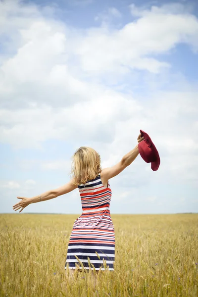 Backview of pretty woman wearing striped dress excited on farm field — Stockfoto