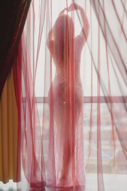 Silhouette of sexy lady on balcony standing with raised hands