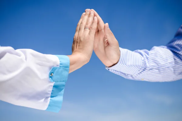 Closeup of nurses hand touching someones hand in striped shirt — Stock Photo, Image