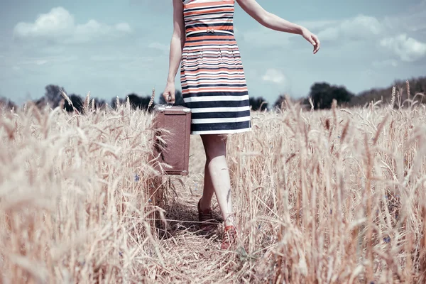 Vintage image of young woman walking on field with suitcase — Stock Photo, Image