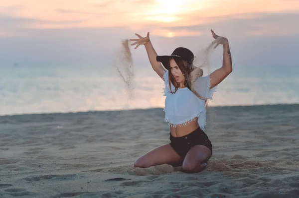 Vzrušená brunetka házení písku ve vzduchu na písečné pláži — Stock fotografie