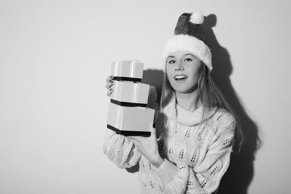 Picture of happy smiling young beautiful lady in Santa hat holding gifts boxes on light copy space background. Black and white photography — Stockfoto