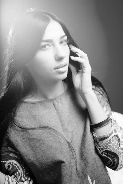 Schwarz-Weiß-Fotografie einer hübschen jungen Frau, die mit dem Handy spricht und sinnlich in die Kamera schaut, während sie Luxushaare auf dem Hintergrund des Kopierraums berührt — Stockfoto