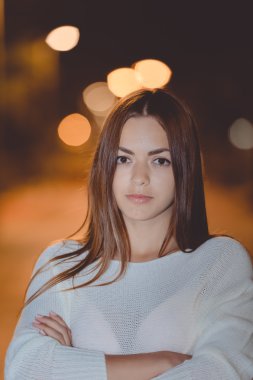 Genç düşünceli esmer gece sokak arka plan üzerinde çapraz el ile