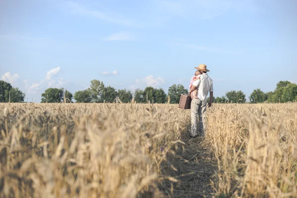 Backview of father hugging baby in golden summer wheat field — Stok fotoğraf
