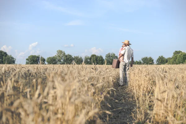 Backview of father hugging baby in golden summer wheat field — 图库照片