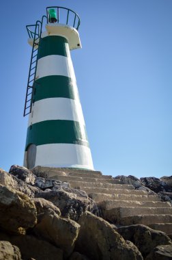 Beautiful lighthouse with bright sun on top on sky background