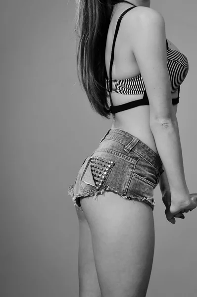 Black and white of beautiful female with perfect shaped body in jeans shorts