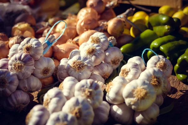 Färsk vitlök klasar grön paprika och lök på marknaden stativ — Stockfoto