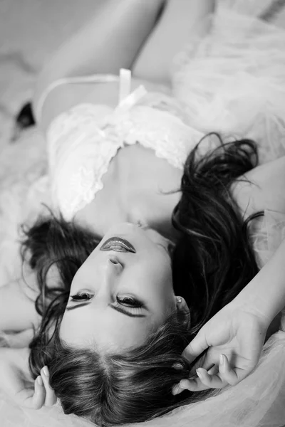 Чорно-біла фотографія красивої молодої леді в нижній білизні, що розслабляється в ліжку — стокове фото