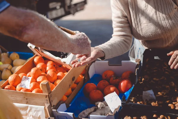 Imagen del mercado con diferentes frutas. Compradores y vendedores mano sobre fondo colorido . — Foto de Stock