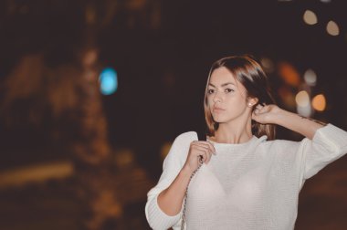 Genç düşünceli esmer gece sokak arka plan üzerinde çapraz el ile