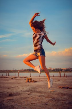 Image of beautiful active young lady having fun jumping high over open water on summer outdoors background copy space