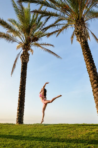 Hermosa joven excitante mujer en bikini saltar bajo dos palmeras . — Foto de Stock