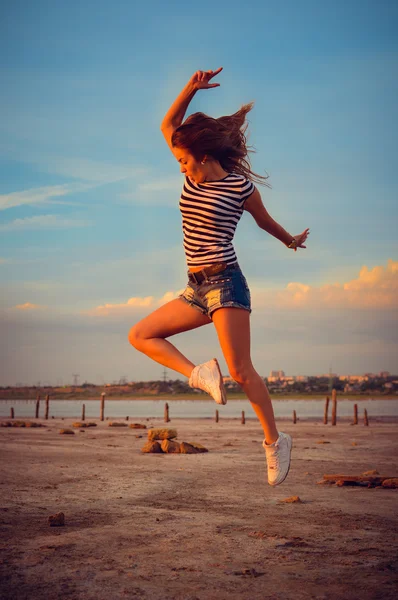 Image of beautiful active young lady having fun jumping high over open water on summer outdoors background copy space — ストック写真