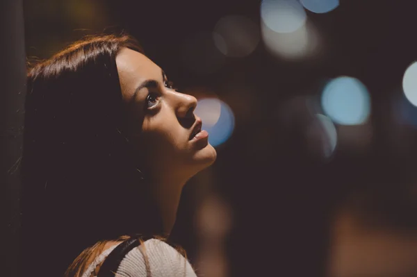 Sad young lady thinking about something leaning against street lamp — Stock Photo, Image