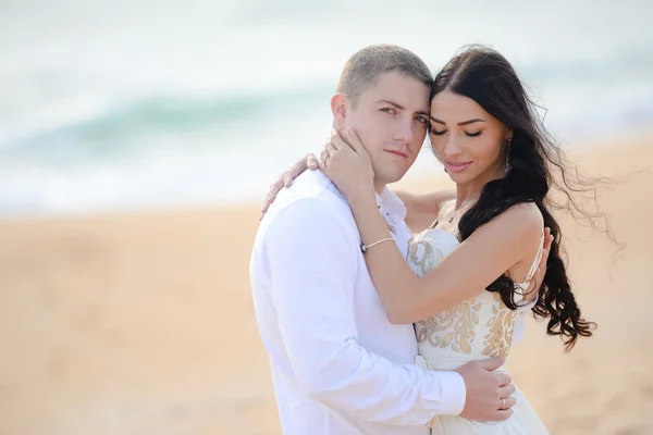 Portrait of young stylish couple kissing on the beach. Wearing luxury fashion outfits, evening sunlight. — Stock fotografie