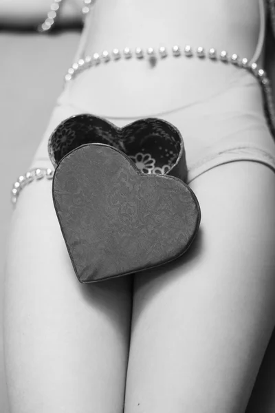 Regalo regalo caja en forma de corazón acostado en las piernas femeninas —  Fotos de Stock