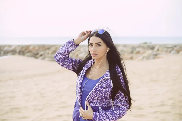 Sport vrouw luisteren muziek op het strand — Stockfoto