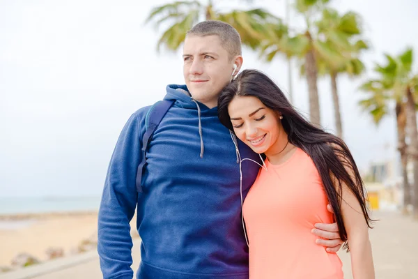 Glückliches Paar küsst und lächelt über Palmen am Strand. — Stockfoto