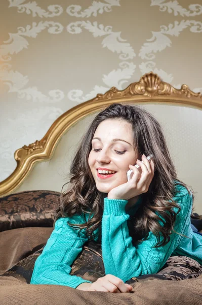 Hermosa joven hablando en el teléfono móvil acostado en la cama sonrisa feliz. Retrato de primer plano — Foto de Stock