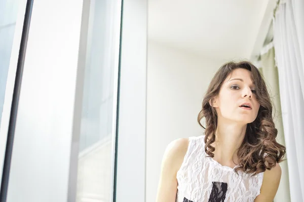 Retrato de una hermosa joven en la ventana — Foto de Stock