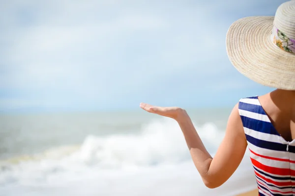 Bakifrån av elegant kvinna håller hand palm upp med sommaren havet i bakgrunden — Stockfoto