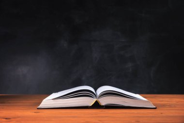 Ağaç masanın üzerinde büyük bir kitap aç.