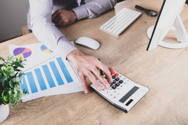 İşçi masasında oturan bir hesap makinesine güveniyor. .