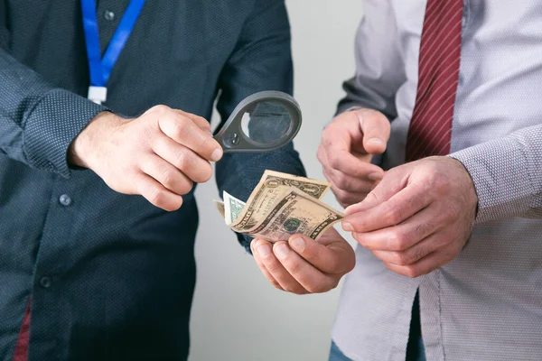 workers check money with a magnifying glass .