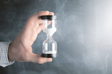 Bir adam elinde kum saati tutuyor. .