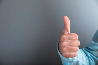 Adam gri arka planda baş parmağını gösteriyor