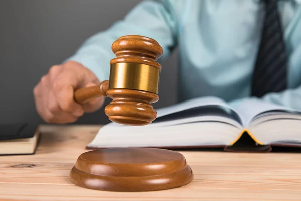 Yargıç gri arka planda çekiçle vuruyor.
