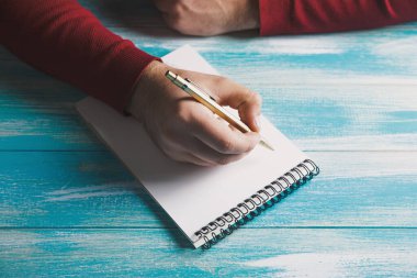 bir deftere yazıyor.